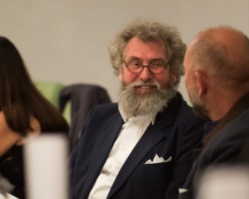 Mehrere Menschen sitzen aufgereiht an einer Tafel