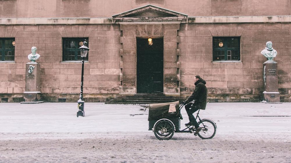 Mann fährt durch leicht schneebedeckte Fahrbarn mit Fahrrad
