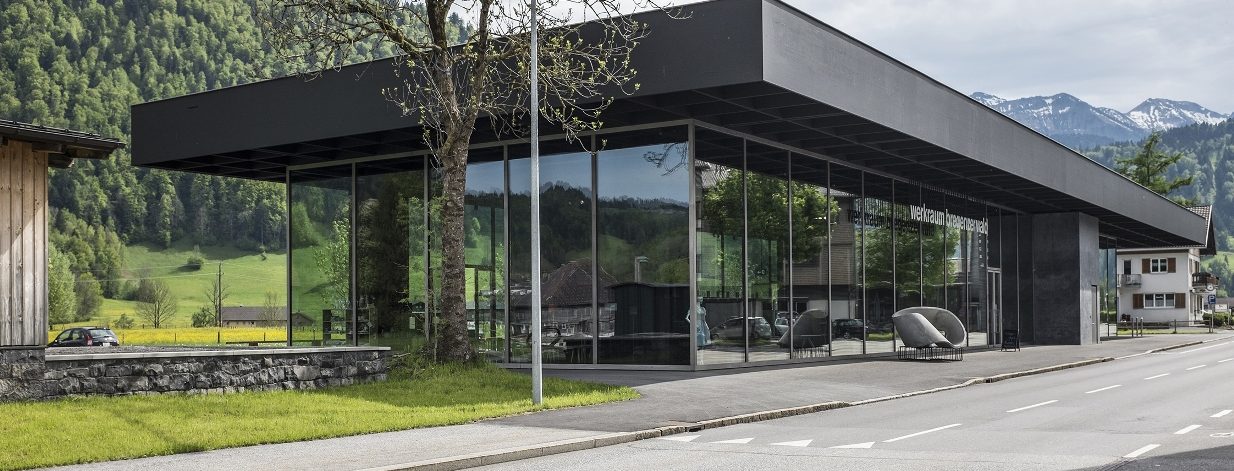 Modernes Gebäude mit viel Glas im Hintergrund schneebedeckte Berge