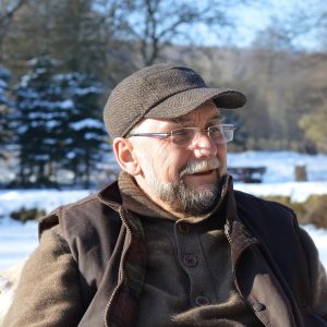 Mann mittleren Alters mit rahmenloser Brille und Bart und Kappe