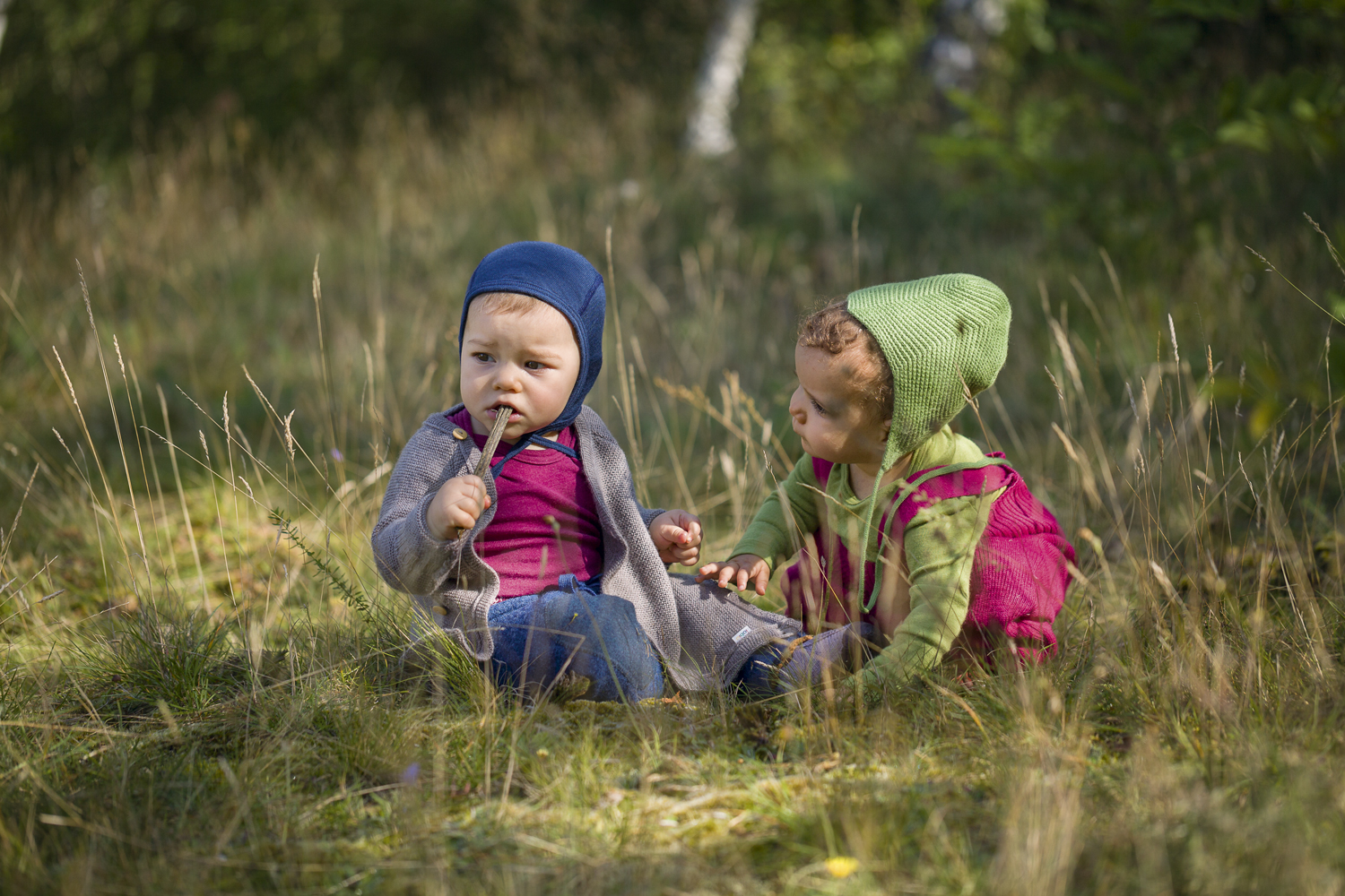 2 Kleinkinder hocken in der Wiese