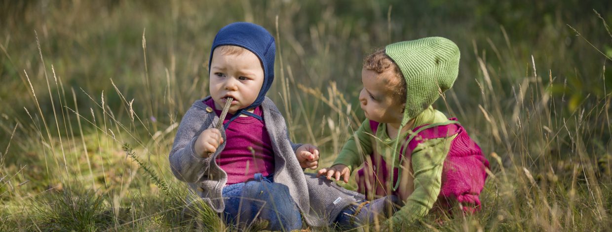 2 Kleinkinder hocken in der Wiese