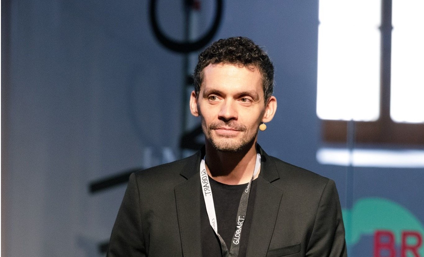 Mann in Anzug kurzen Haaren und getrimmtem Bart steht auf einer Bühne