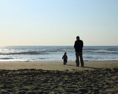 Mann und Kind stehen vor Meer