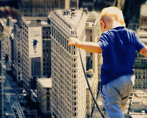 Kleinkinde balanciert über hohes Drahtseil zwischen Hochhäusern