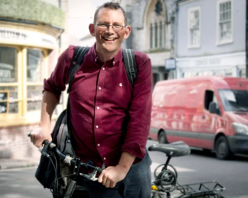 Freundlicher Mann mit rotem Hemd stützt sich auf Rad