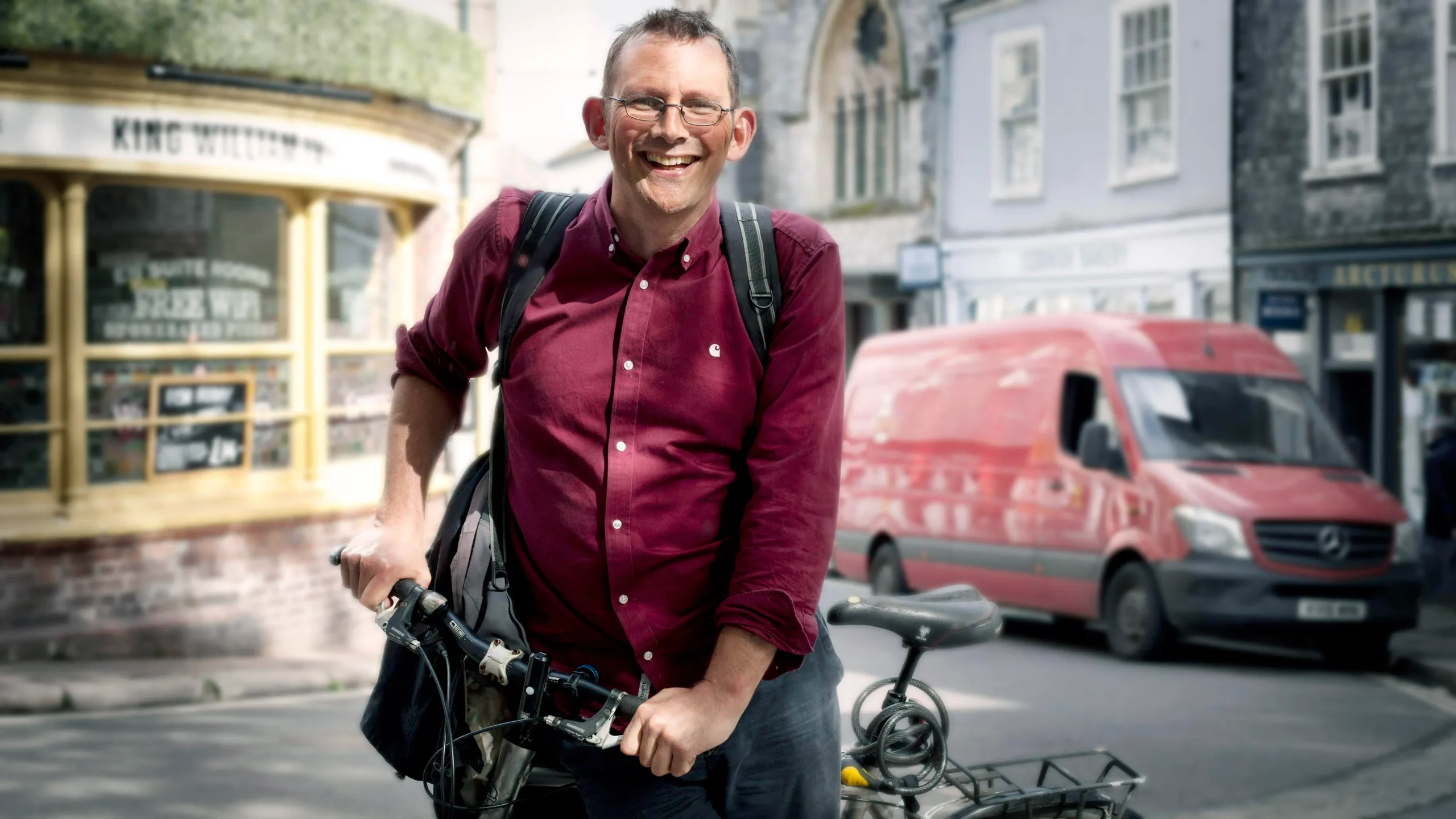 Freundlicher Mann mit rotem Hemd stützt sich auf Rad
