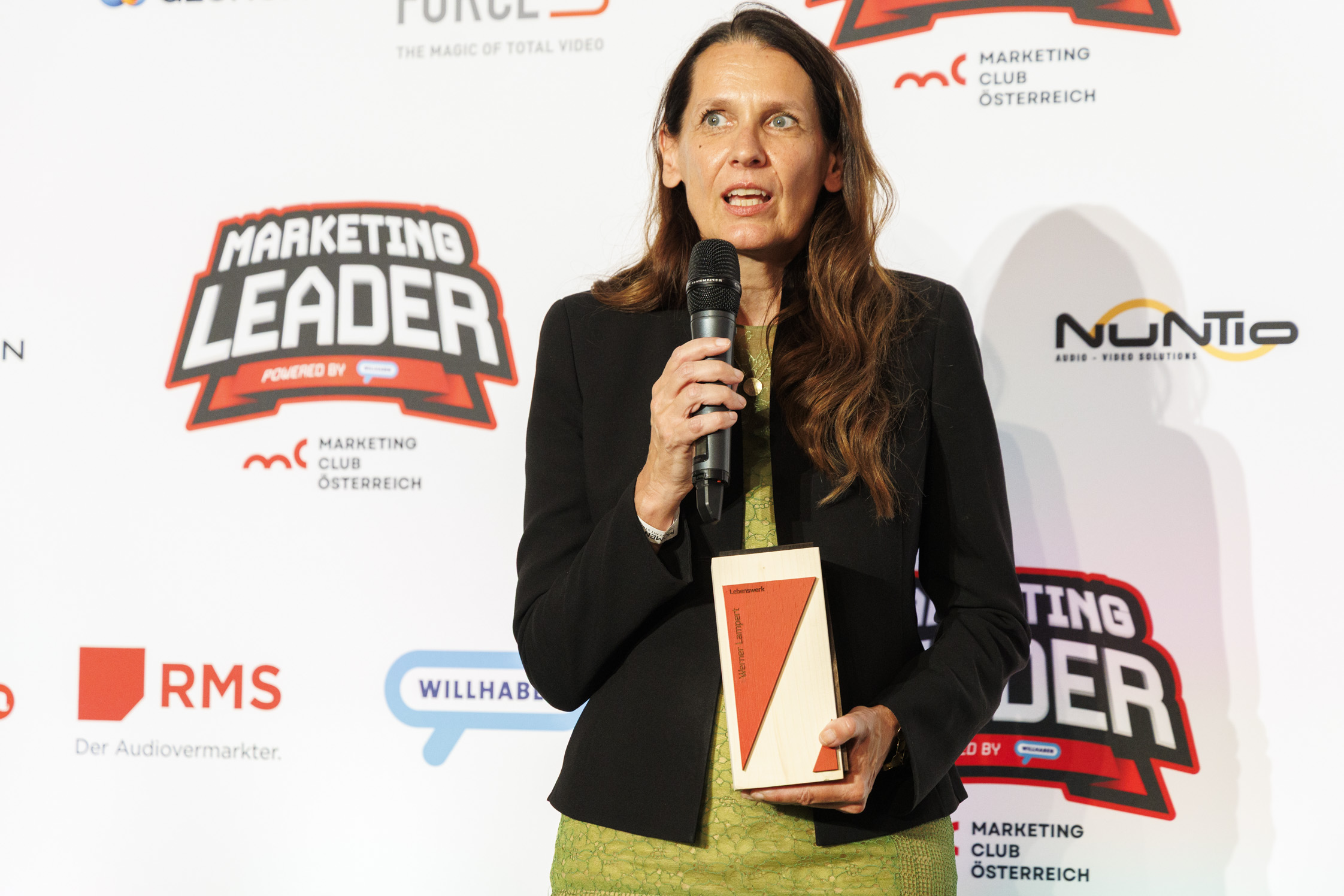 Frau mit langen Haaren spricht mit Mikfrofon