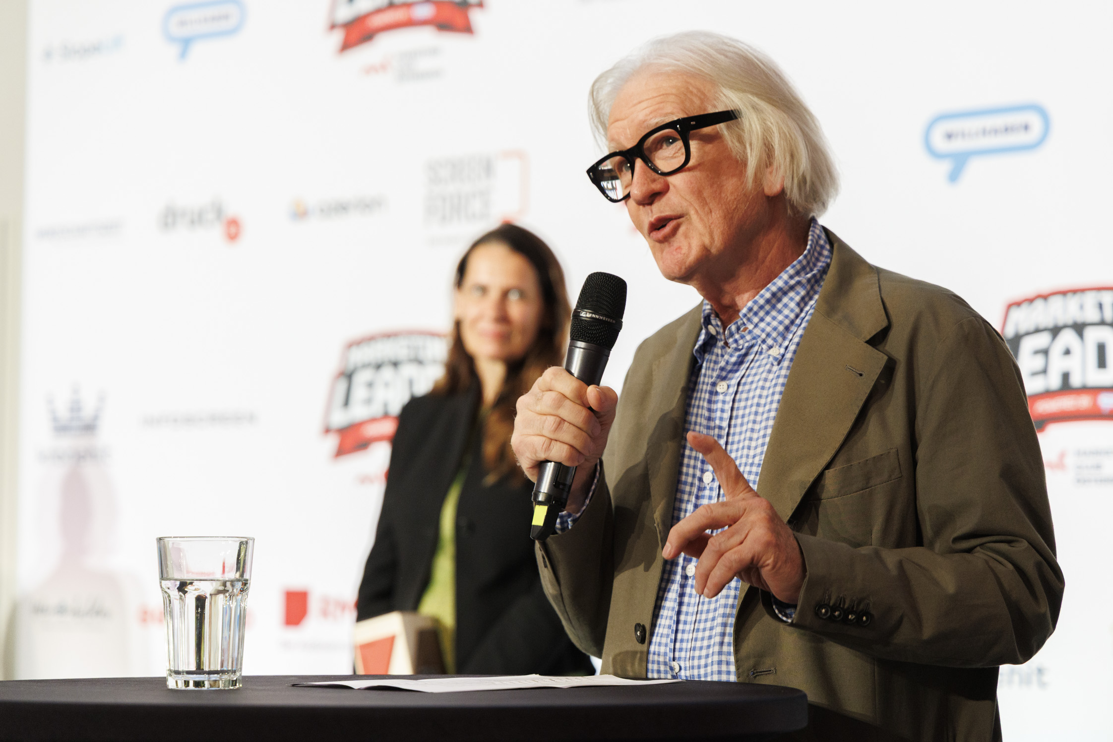 Herr mit schwarzer Brille und weißen Haaren spricht mit Mikrofon