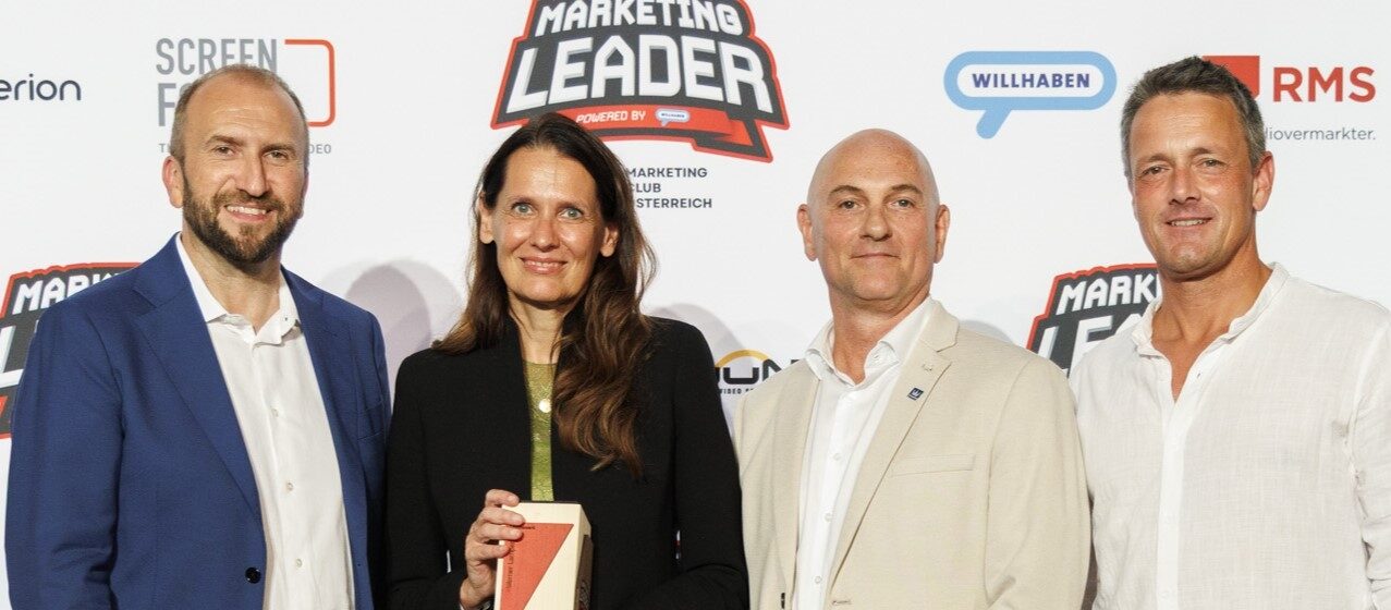 4 Personen lächeln in die Kamera und halten Preis aus Holz in der Hand